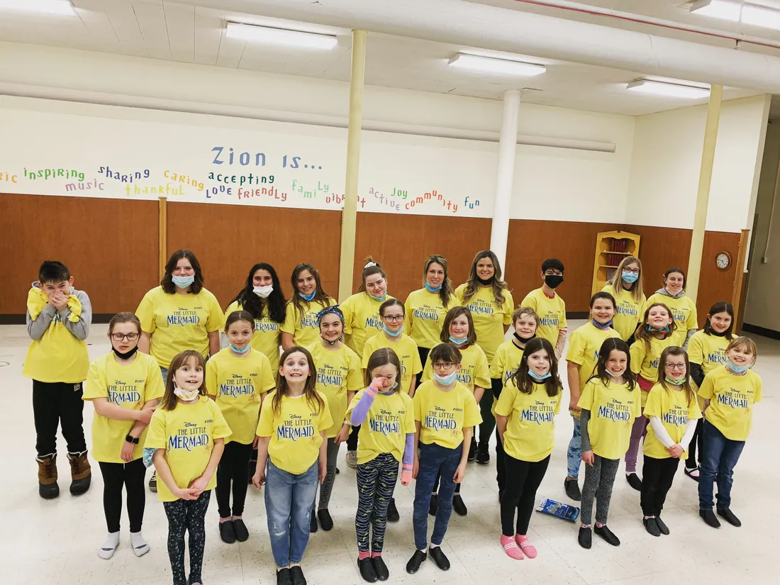 Cast of young performers smiling together after a show.